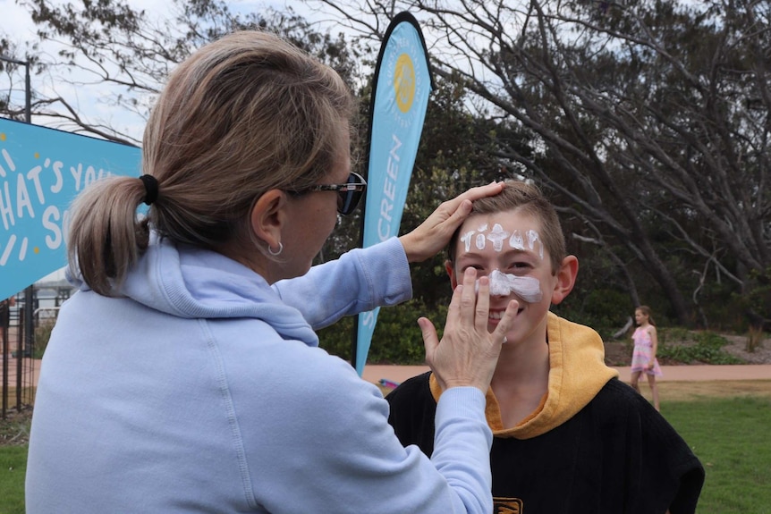 Mum applying sunscreen on her son's face