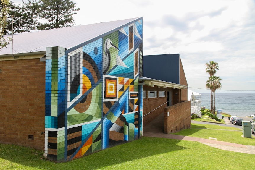 A brightly coloured building faces the sea. 