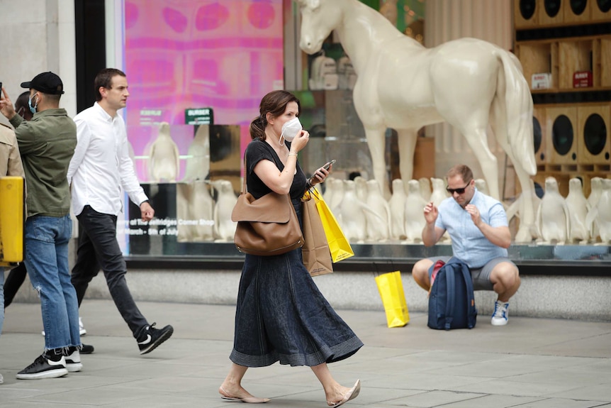 People walk with bags after shopping at the Selfridges department store in London.