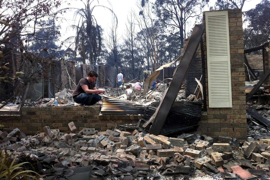 The Kozumplik family sift through the remains of their home in Winmalee.