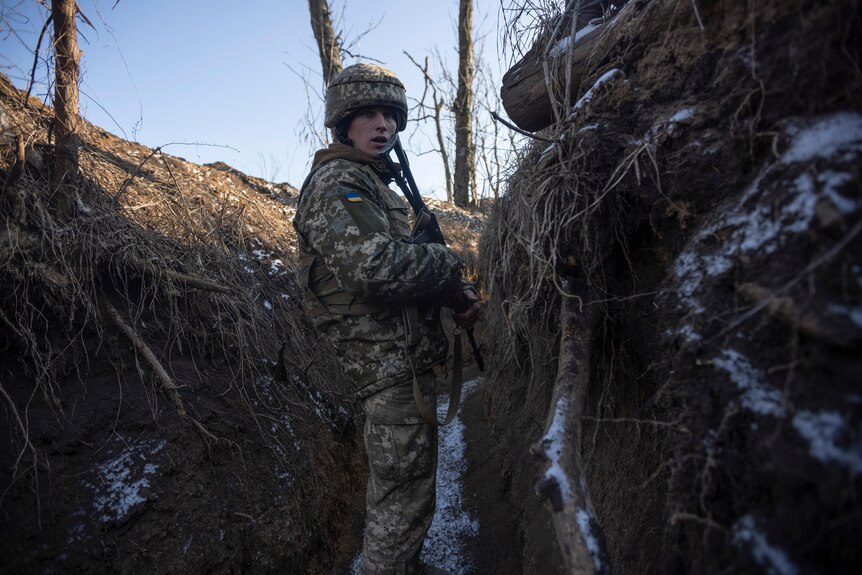 A Ukrainian soldier stands in a trench.