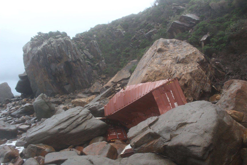 A red, mangled container on stuck on rocks.
