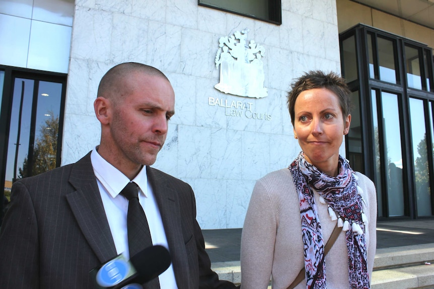 Christian Ashby, wearing a suit, stands next to his wife as he speaks to the media on the steps of court in Ballarat.