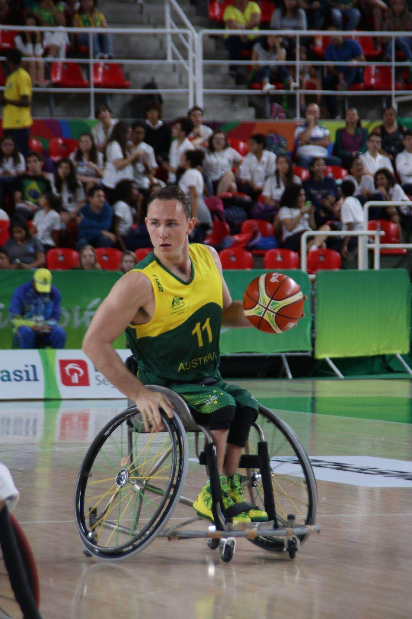 A man dribbling the ball in a wheelchair basketball game.