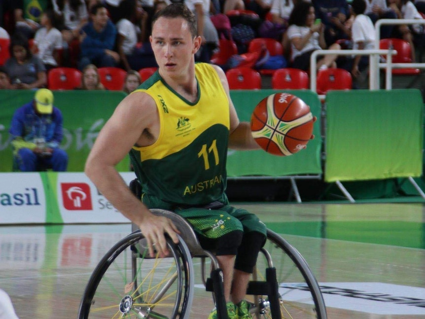 A  man dribbling the ball in a wheelchair basketball game.