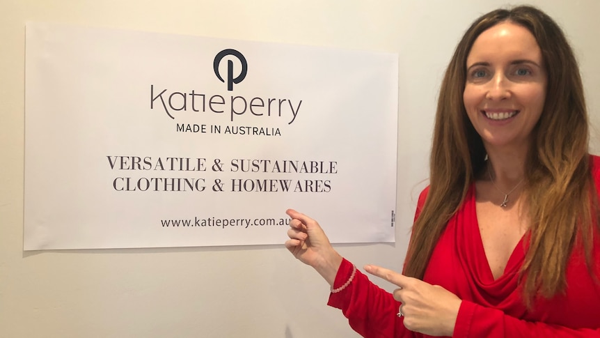 A woman smiles next to a sign