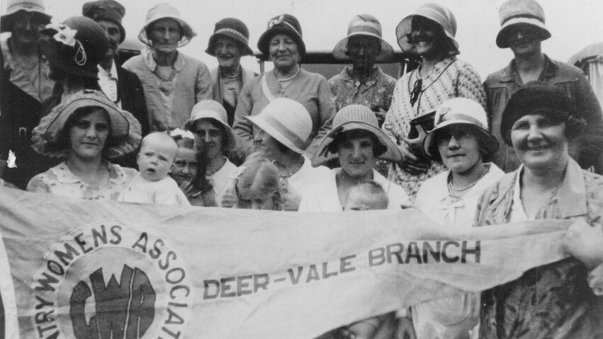 b&w photo, group of smiling women in hats, varying ages, some holding babies +  children,