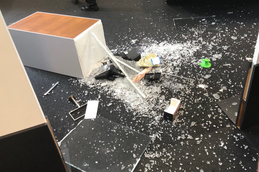 Smashed glass and an overturned desk.
