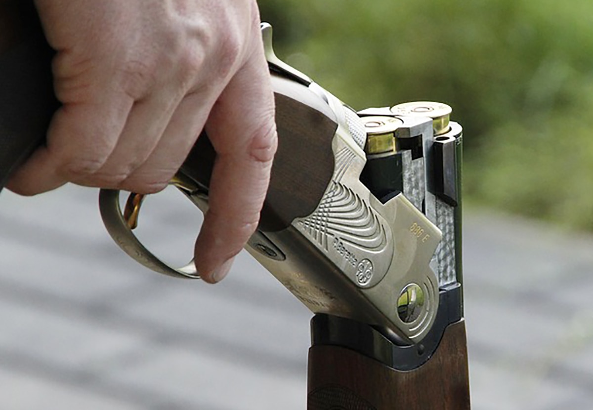 Mão masculina segurando a espingarda.