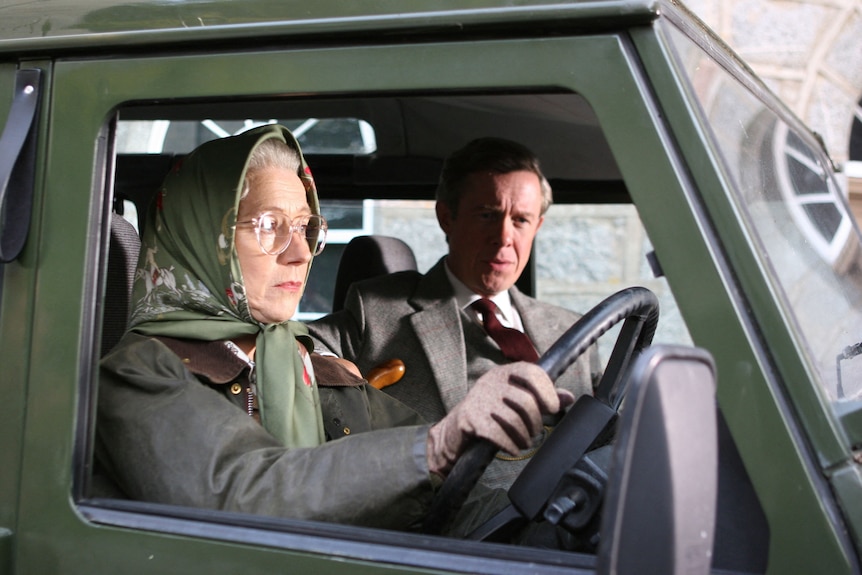 Helen wears a scarf on her head like the Queen and drives a green Jeep with a male passanger next to her