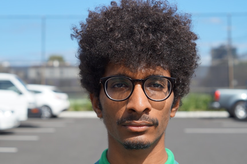 Man with an afro and black rimmed glasses
