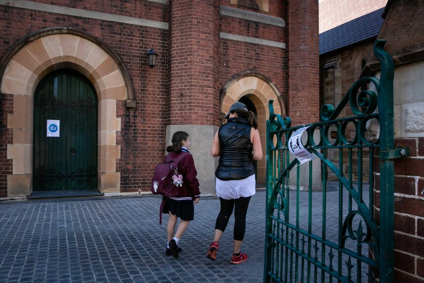 A mother and child walk through a school gate