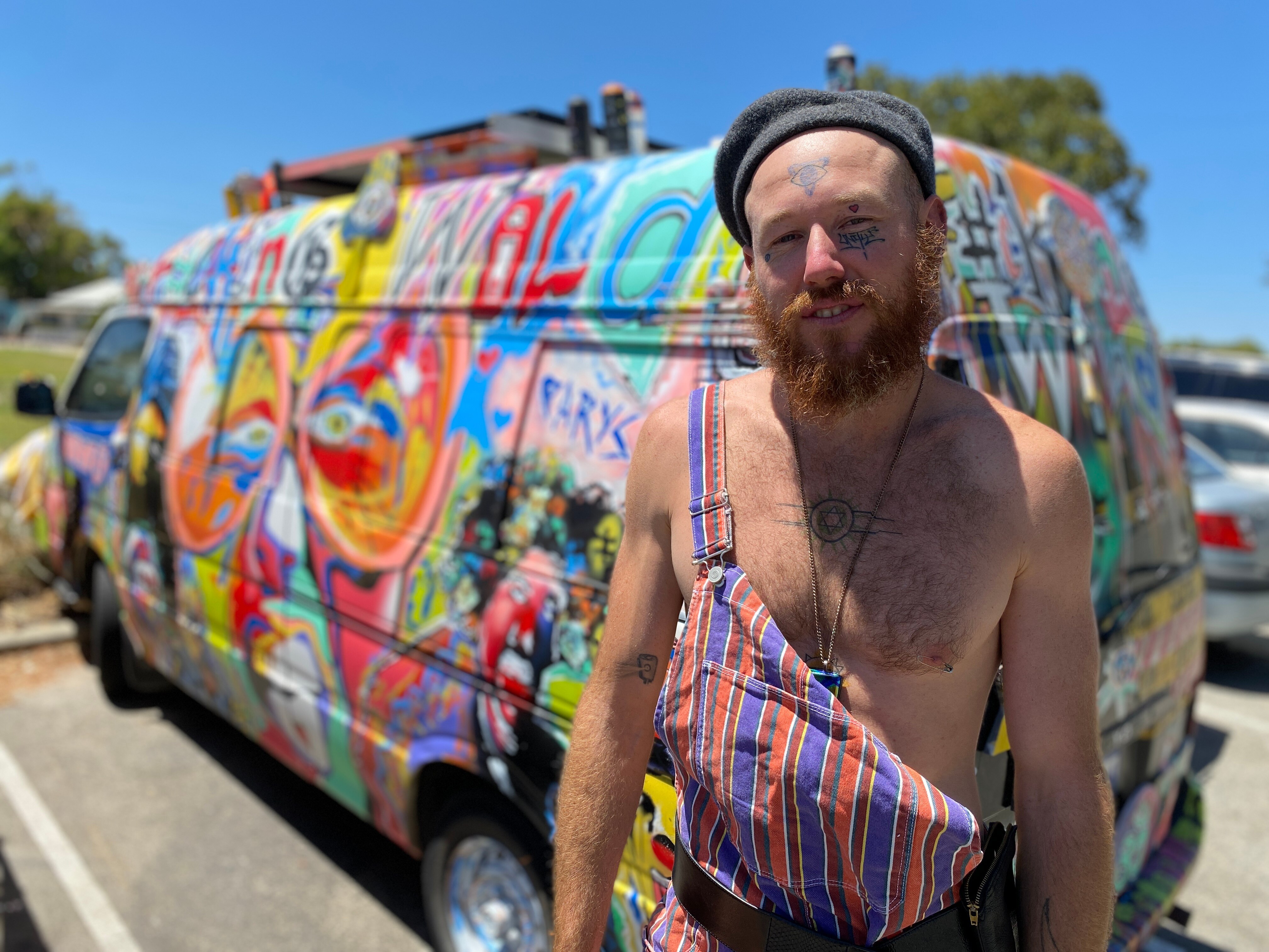 man standing in front of a very colourful camper van