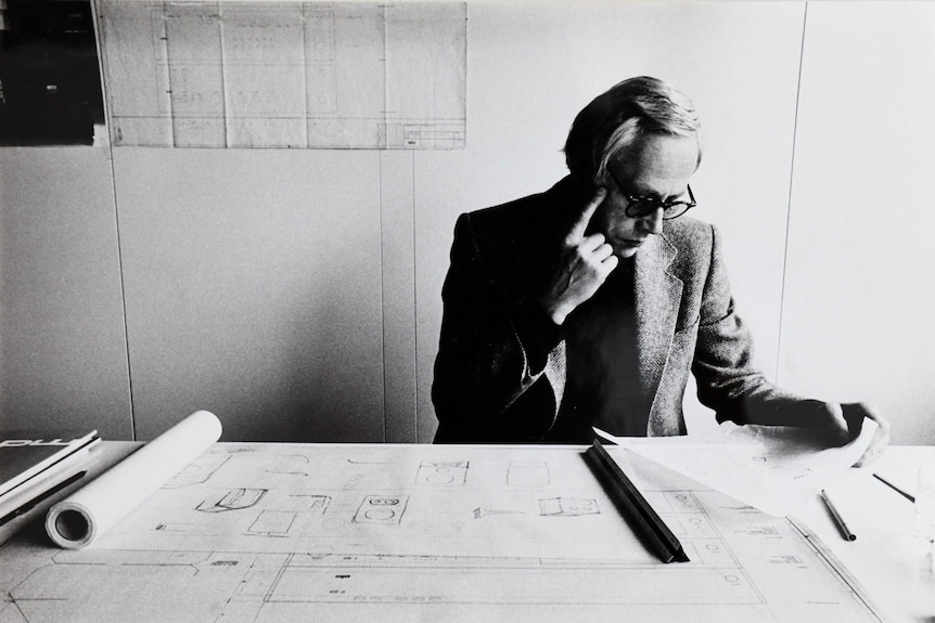 A black and white photo of a man looking at design plans.