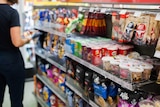 A person looks at a packet of chips in a supermarket or convenience store.