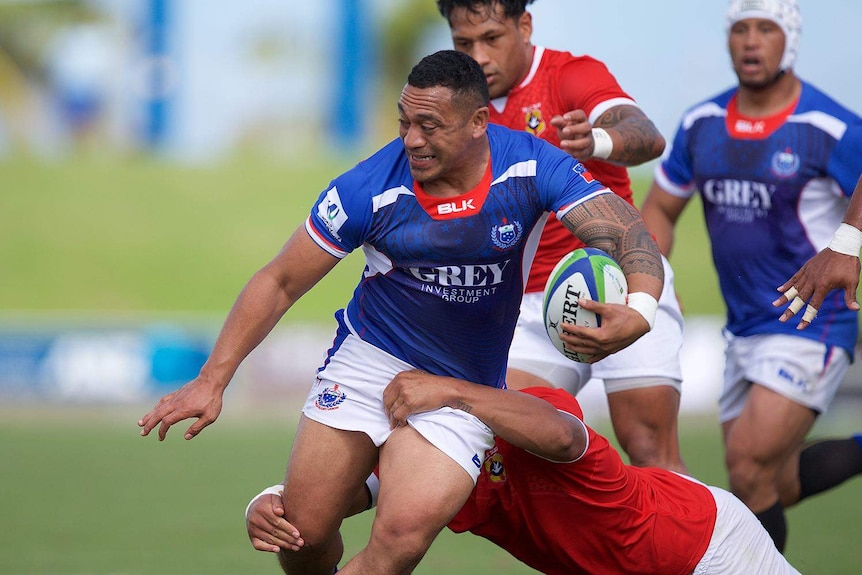 One player tackles another player holding a ball.