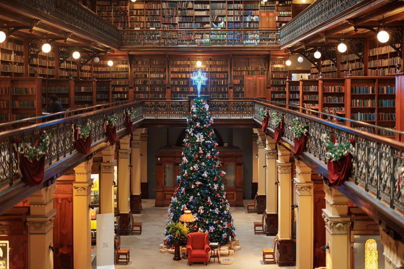 Un enorme árbol de Navidad de dos plantas en medio de una gran biblioteca
