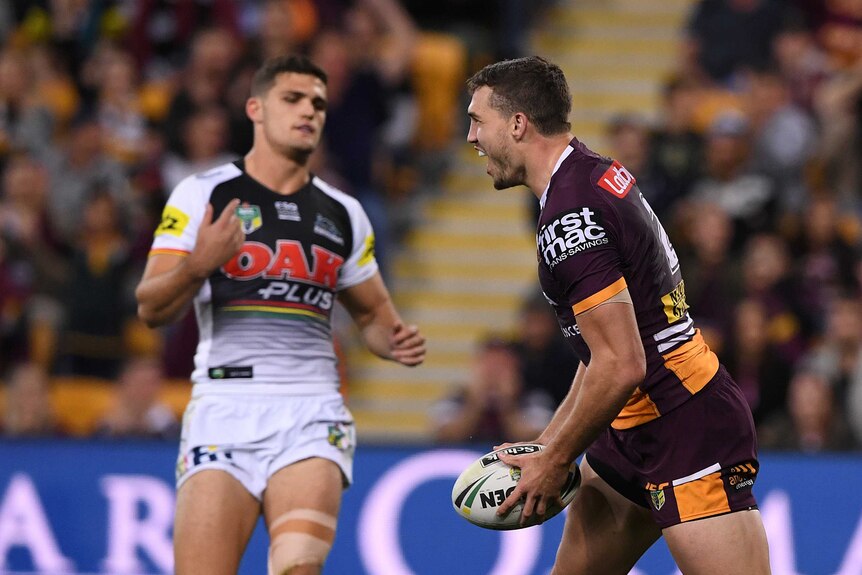 Corey Oates celebrates a try with the ball in his hand, as Nathan Cleary looks on.