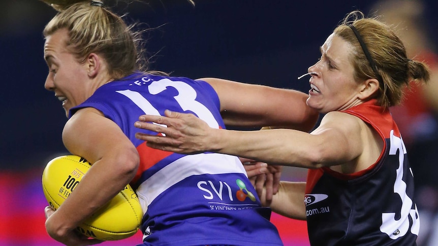 Lauren Arnell of the Bulldogs is tackled by Bree White of Demons in women's AFL exhibition match.