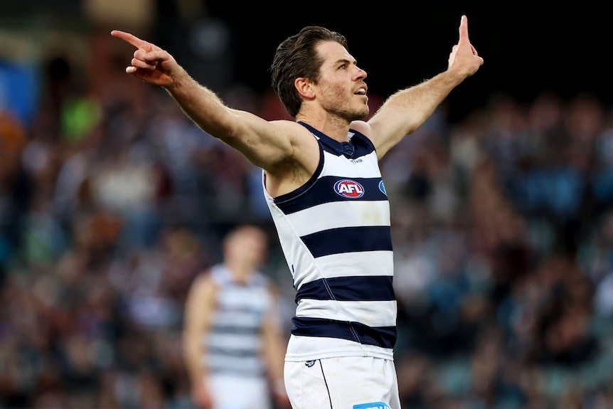 Seorang pemain Geelong Cats AFL berdiri dengan tangan terentang saat merayakan gol.