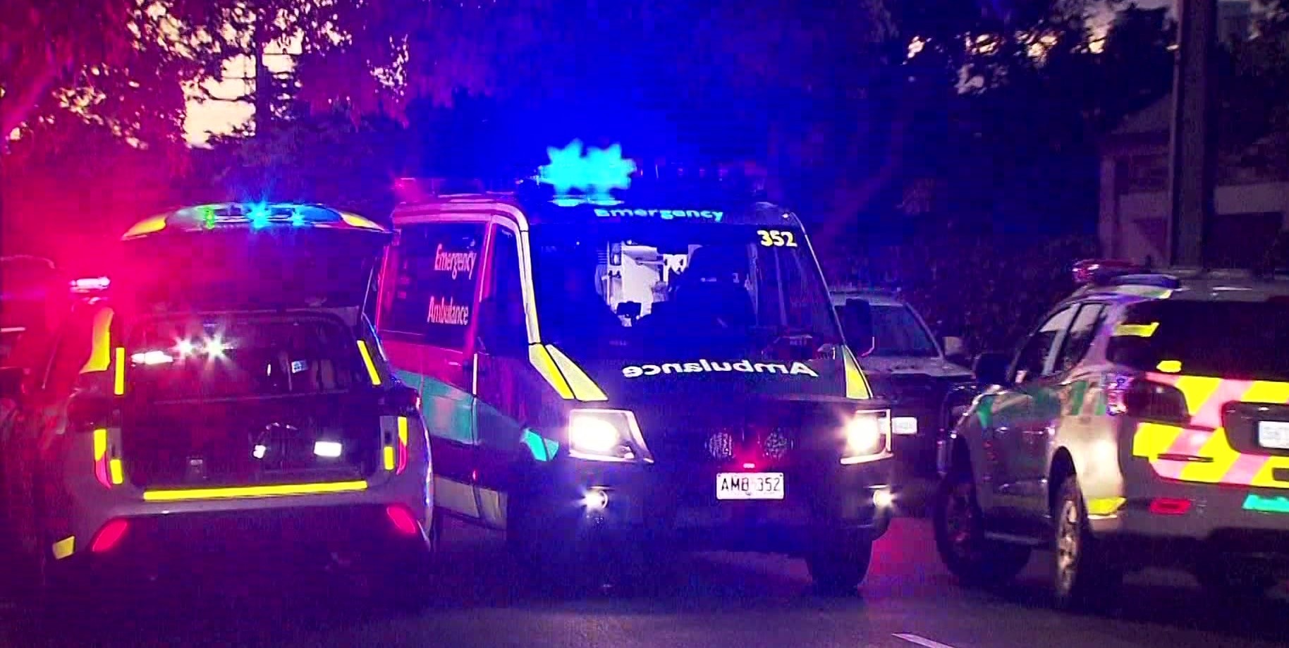 Numerous ambulances vehicles on a street at night