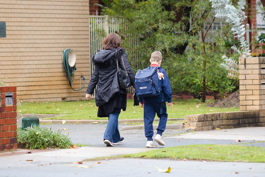 A young male student with a backpack on walks along a footpath next to a woman.