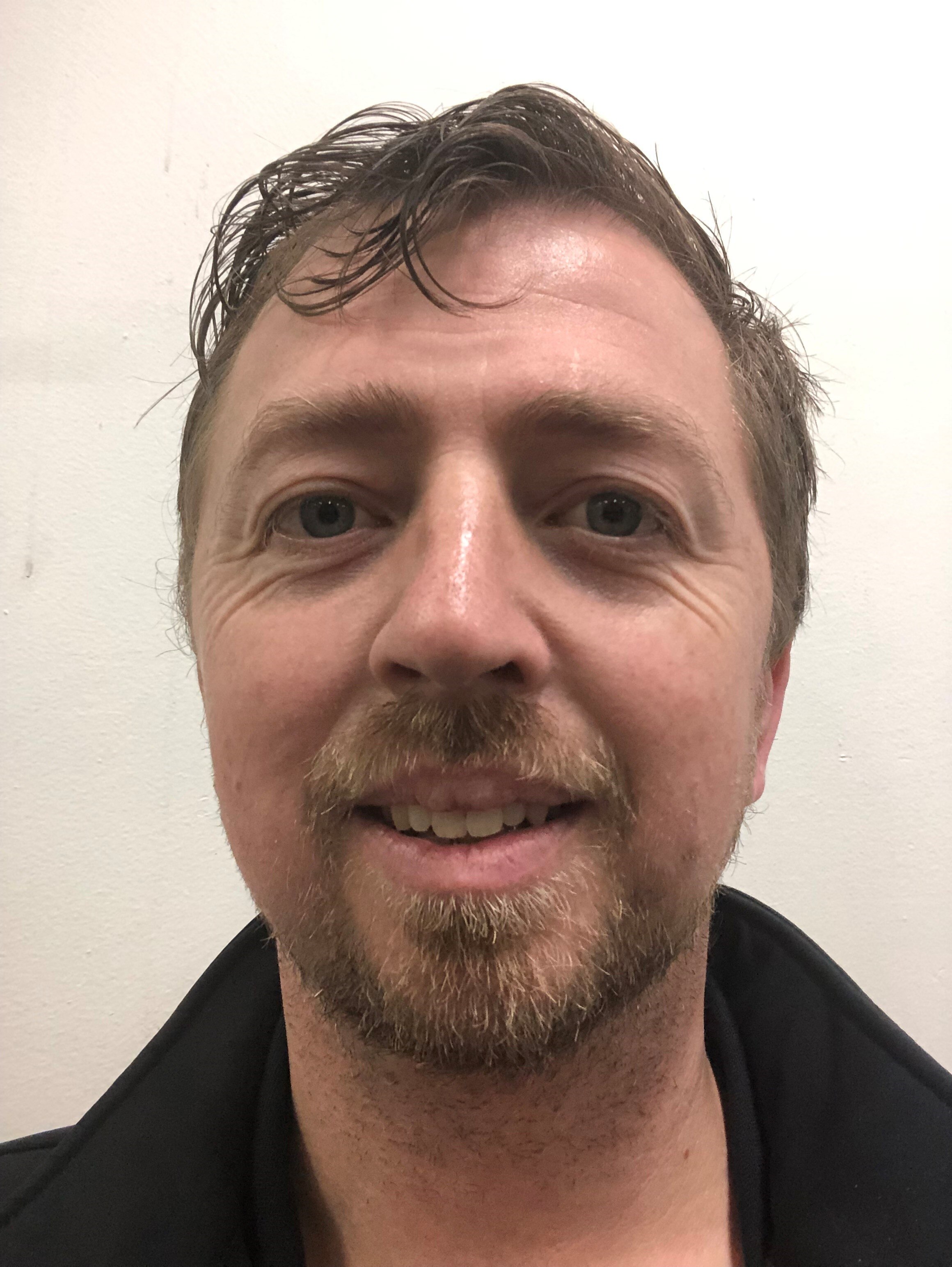 A headshot of a man with dark hair and a neat beard.