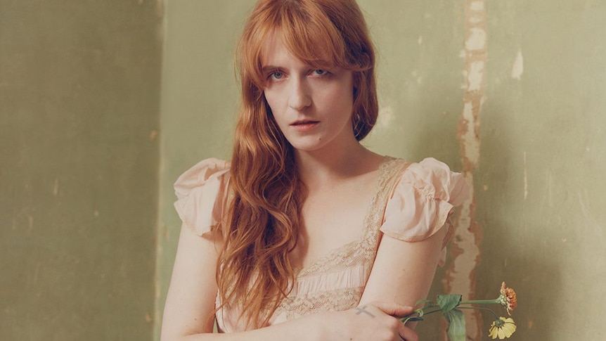 Florence Welch holds two flowers