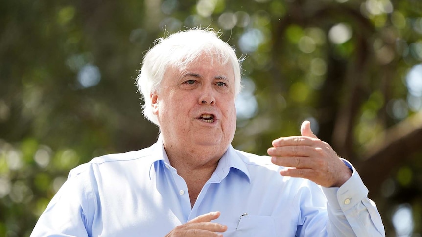 A man with white hair wearing a business shirt in mid-conversation