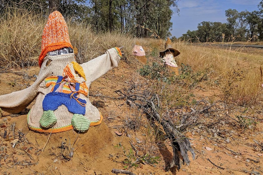 A termite mound dressed in a woollen jumper on the roadside of an outback highway.