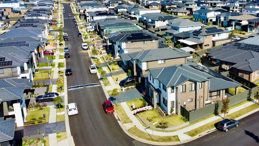 An aerial view of a street lined with newly built houses on a sunny day.