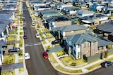 An aerial view of a street lined with newly built houses on a sunny day.