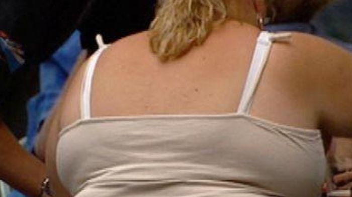 A very obese woman sits on chair at a cafe.