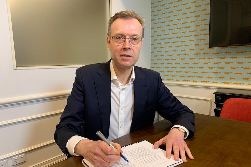 A man in a suit writing on a piece of paper.