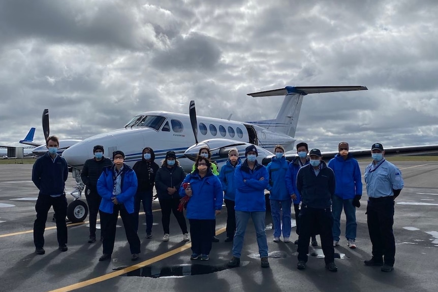 Health staff standing infront of an aircraft