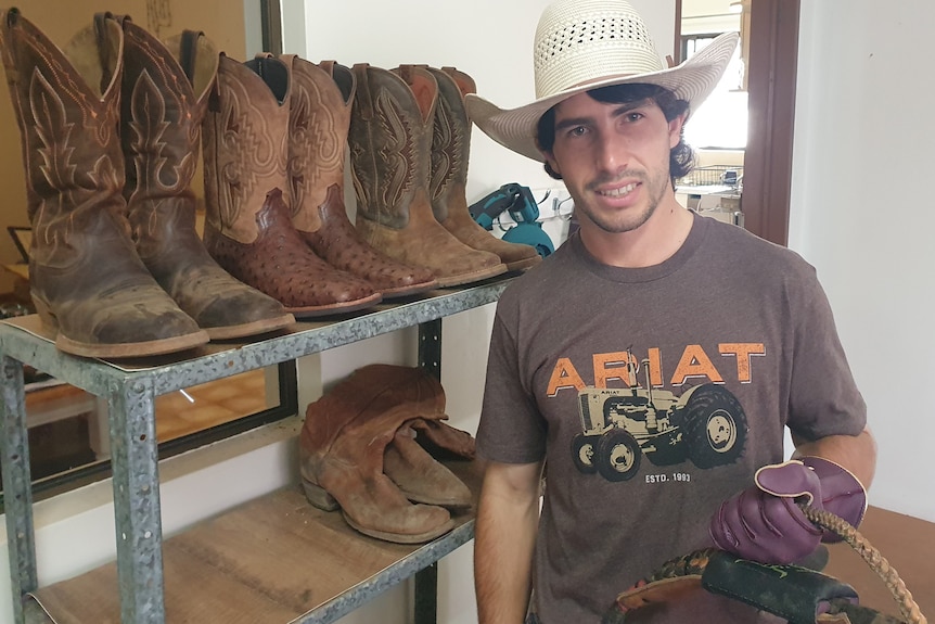 Man standing in front of a shelf of cowboy boots
