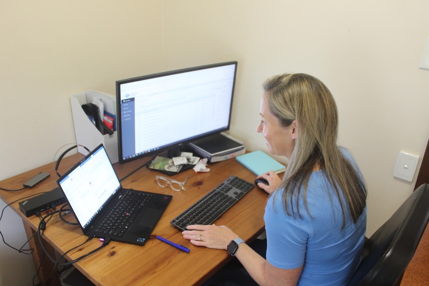 A woman smiling as she works at a desk. 