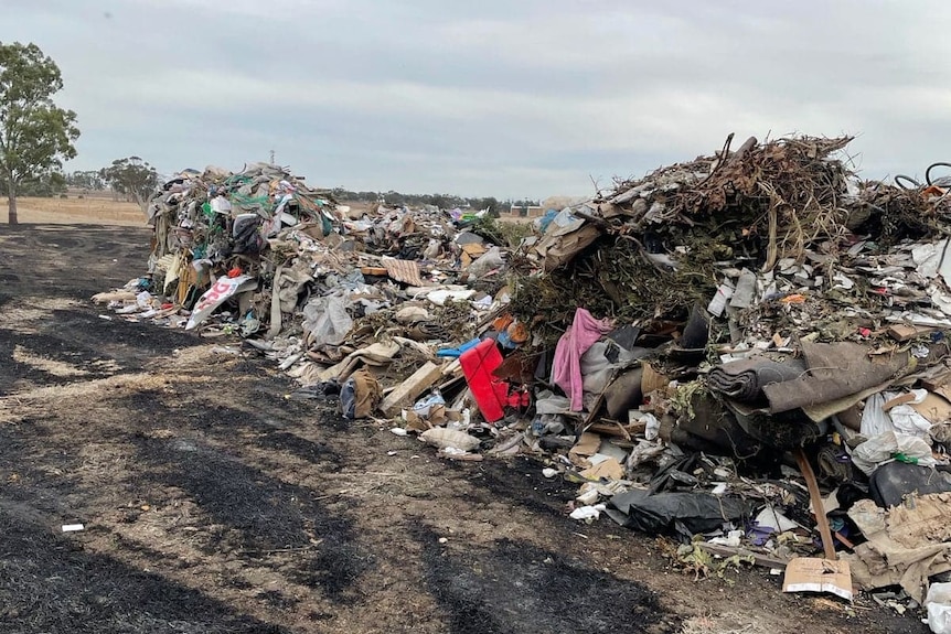 Large pile of rubbish, 3 metres high, burnt ground