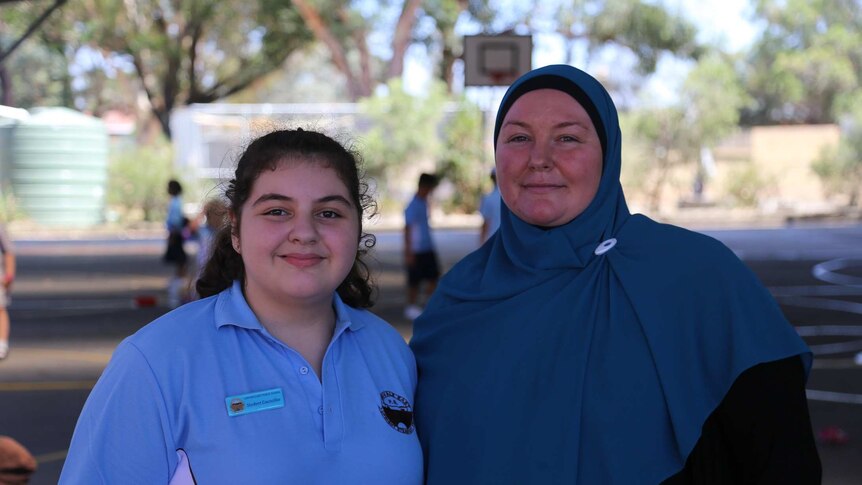 A mother with her daughter, who is wearing a school uniform.