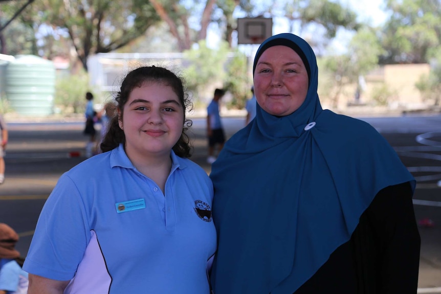 A mother with her daughter, who is wearing a school uniform.