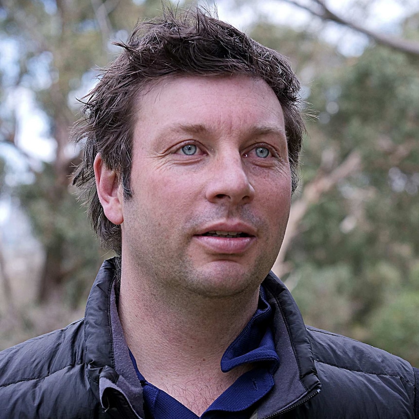 Tim Smith poses for a portrait, with trees in the background