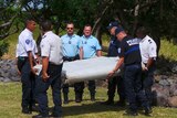 French gendarmes and police carry a large piece of plane debris