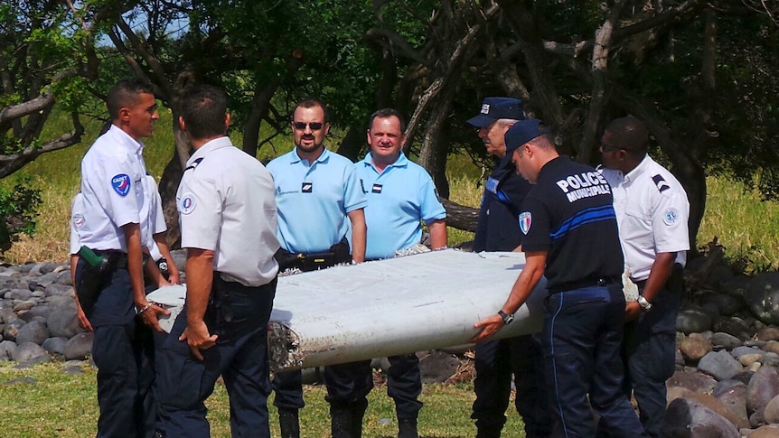 Police carry a large piece of plane debris found on La Reunion in July 2015.