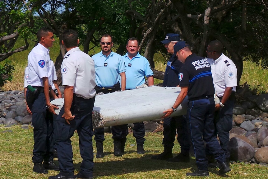 Police carry a large piece of plane debris found on La Reunion in July 2015.