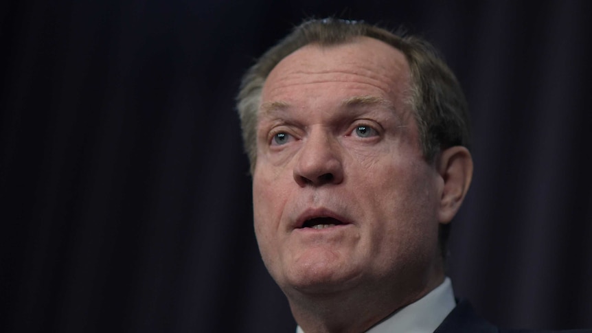 Chris Jordan, standing in front of a black background, speaks during a press conference at Parliament House in Canberra