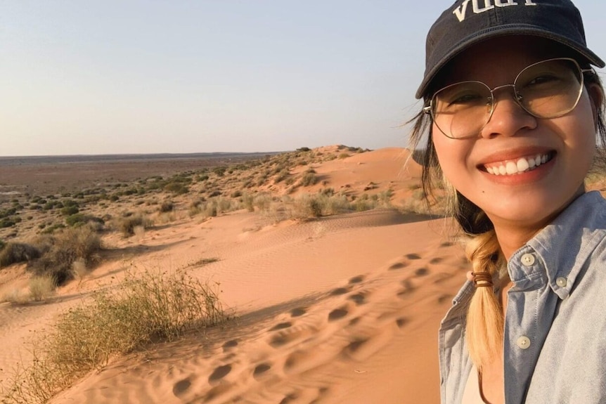 Joy taking a selfie smiling on a red sand dune. 