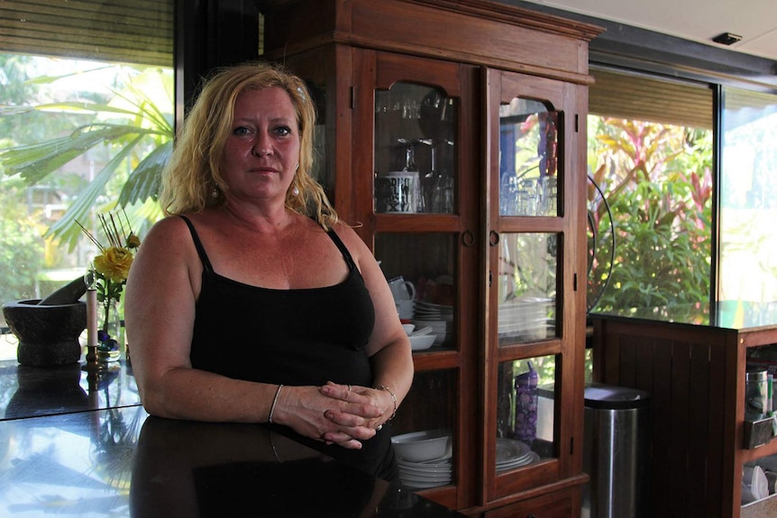 A photo of small business owner Gaynor Beck leaning on her kitchen counter in her breezy, tropical kitchen.