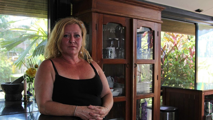 A photo of small business owner Gaynor Beck leaning on her kitchen counter in her breezy, tropical kitchen.