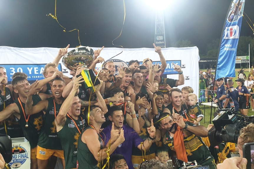 St Mary's players and coaches hold up the premiership cup.