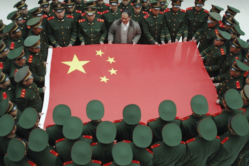 Paramilitary soldiers hold a Chinese national flag along with Jiang Xinglin at an army base.